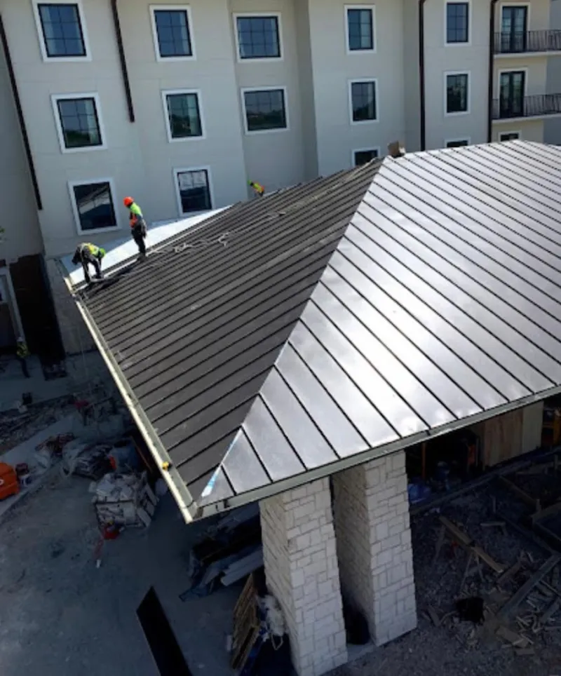 Crew installing standing seam metal roof panels on a commercial project in Liberty